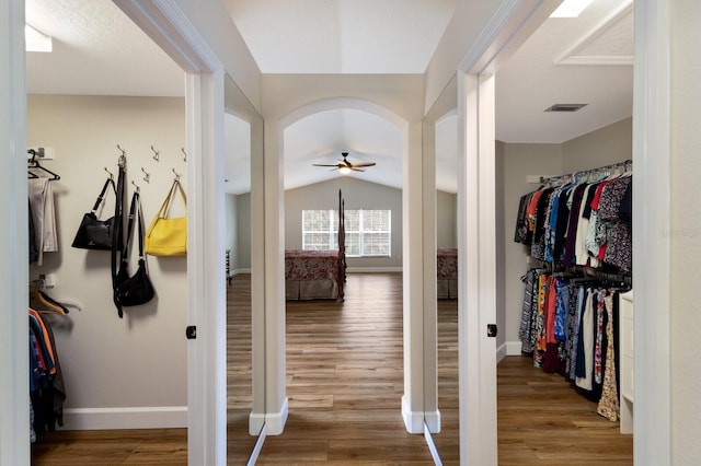 interior space with lofted ceiling, arched walkways, wood finished floors, visible vents, and baseboards