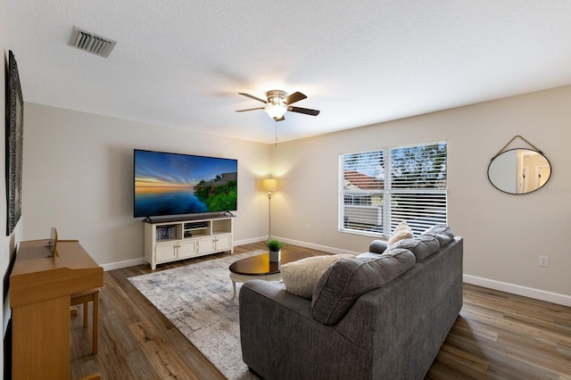 living area featuring a ceiling fan, wood finished floors, visible vents, and baseboards