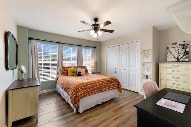 bedroom with a ceiling fan, a closet, baseboards, and wood finished floors