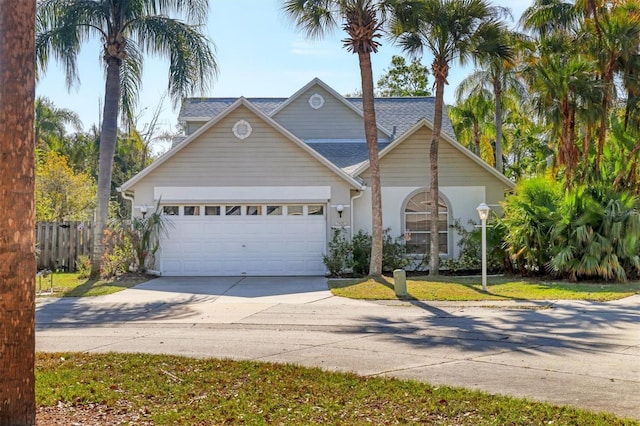 traditional home featuring driveway, a shingled roof, an attached garage, and a front yard