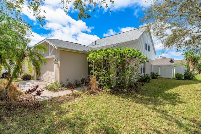 view of property exterior featuring driveway, an attached garage, a gate, a yard, and stucco siding