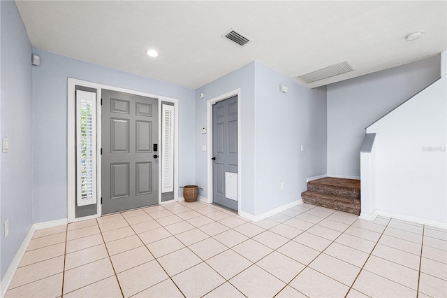 foyer entrance with stairs, visible vents, baseboards, and light tile patterned floors