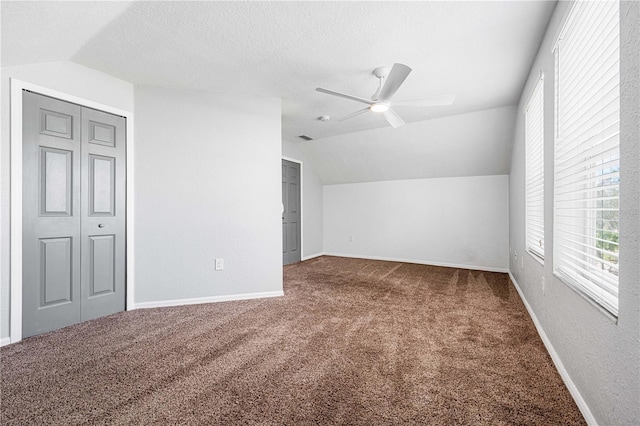 additional living space featuring carpet floors, a ceiling fan, vaulted ceiling, a textured ceiling, and baseboards