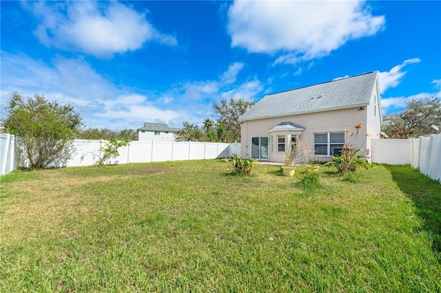 rear view of property featuring stucco siding, a fenced backyard, and a yard