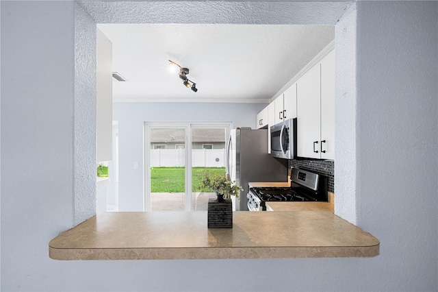 kitchen with a textured wall, visible vents, white cabinets, appliances with stainless steel finishes, and backsplash