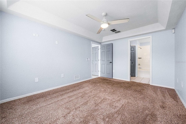 unfurnished bedroom featuring light colored carpet, baseboards, visible vents, and a tray ceiling