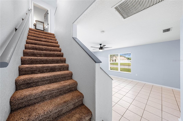 stairway featuring baseboards, tile patterned flooring, visible vents, and a ceiling fan