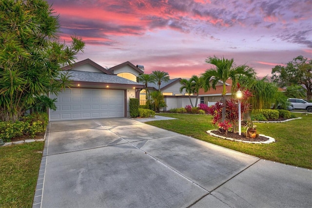 ranch-style house featuring a garage, concrete driveway, a front yard, and stucco siding