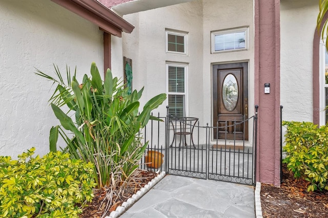 entrance to property with a gate and stucco siding