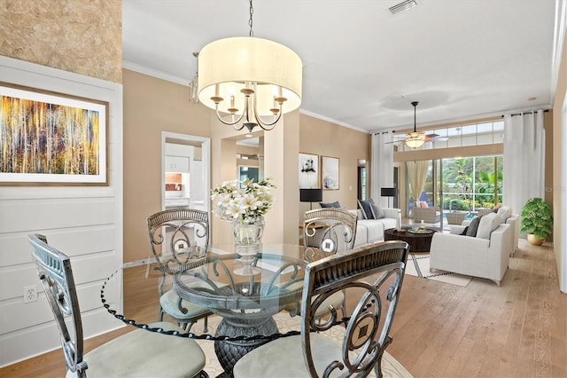 dining area featuring light wood finished floors, ornamental molding, ceiling fan with notable chandelier, and visible vents