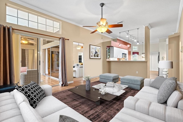 living room featuring ceiling fan, visible vents, crown molding, and wood finished floors