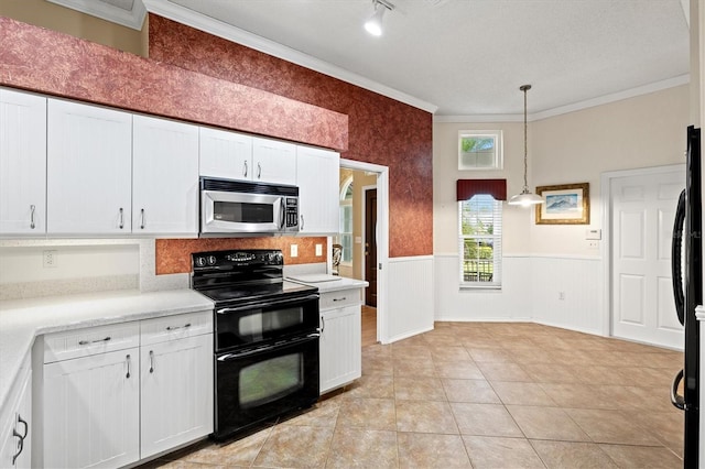 kitchen with light countertops, hanging light fixtures, wainscoting, white cabinetry, and black appliances