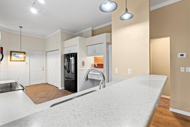 kitchen featuring hanging light fixtures, black fridge, light countertops, and crown molding