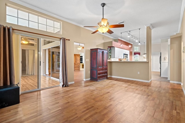 unfurnished living room with baseboards, visible vents, ceiling fan, light wood-style flooring, and crown molding