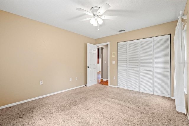 unfurnished bedroom with carpet floors, a closet, visible vents, a ceiling fan, and baseboards