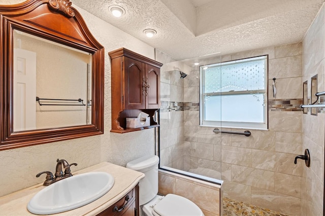 bathroom with a textured wall, walk in shower, a textured ceiling, and vanity