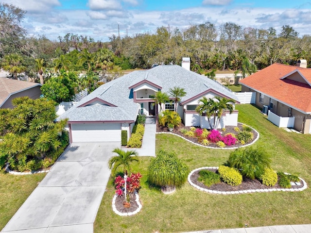 view of front of property with a garage, a shingled roof, concrete driveway, and a front yard