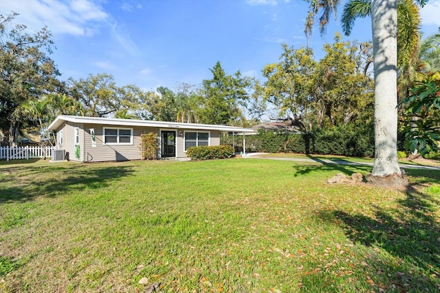 exterior space with central AC unit, fence, and a front lawn