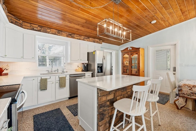 kitchen featuring appliances with stainless steel finishes, wood ceiling, a sink, a kitchen island, and a kitchen breakfast bar