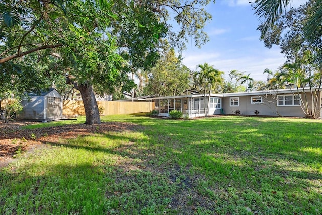 view of yard featuring an outdoor structure, a sunroom, fence, and a storage shed