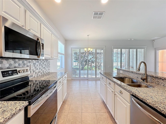 kitchen with stainless steel appliances, a sink, visible vents, white cabinets, and tasteful backsplash