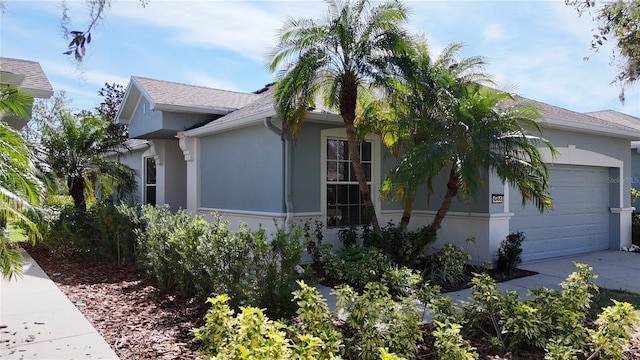 view of side of home featuring a garage, concrete driveway, roof with shingles, and stucco siding