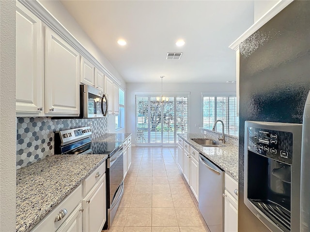 kitchen featuring light tile patterned floors, a sink, visible vents, appliances with stainless steel finishes, and backsplash