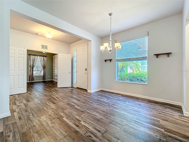 unfurnished room with baseboards, plenty of natural light, visible vents, and wood finished floors