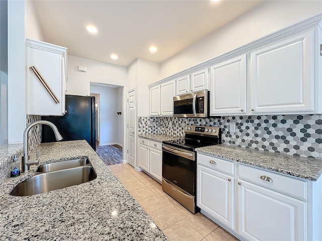 kitchen featuring appliances with stainless steel finishes, white cabinetry, a sink, and backsplash