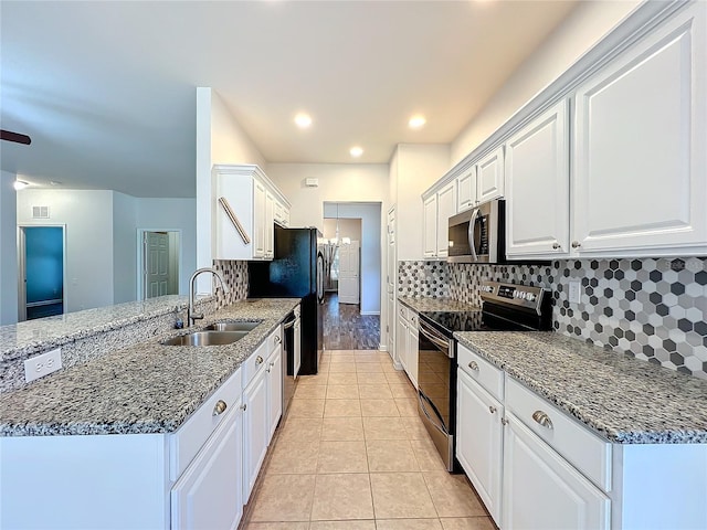 kitchen with light tile patterned flooring, stainless steel appliances, a sink, white cabinetry, and backsplash