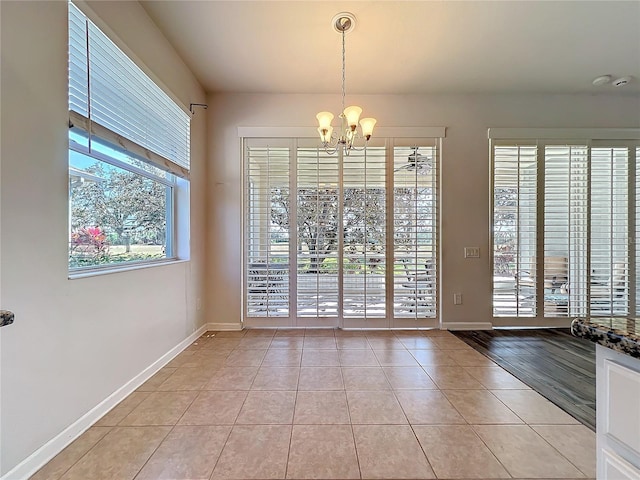 interior space with light tile patterned floors, baseboards, and an inviting chandelier