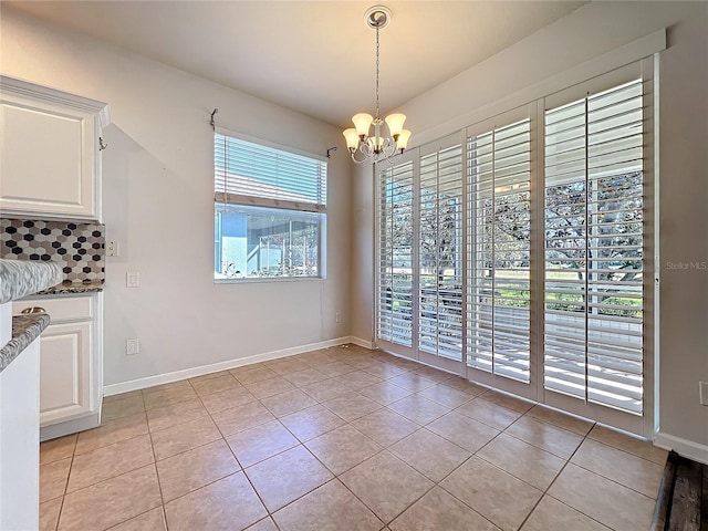 unfurnished dining area with light tile patterned floors, baseboards, and a notable chandelier