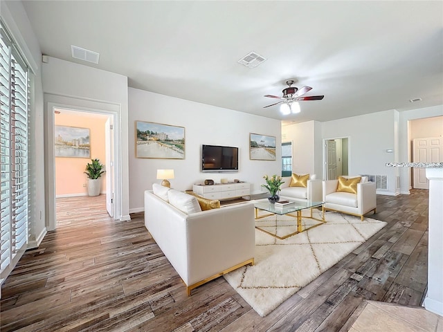 living area featuring a ceiling fan, visible vents, and wood finished floors