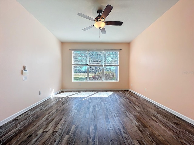 empty room featuring a ceiling fan, dark wood finished floors, and baseboards