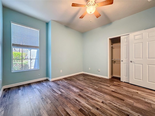 unfurnished bedroom featuring dark wood-style floors, ceiling fan, a closet, and baseboards