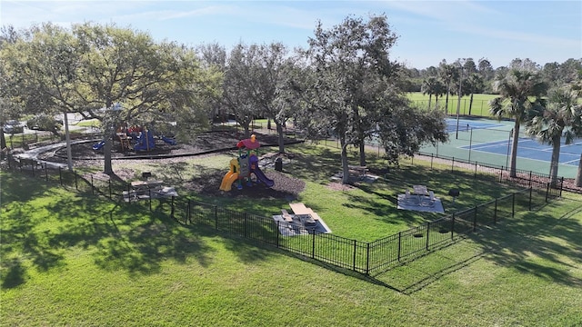 view of community featuring playground community, a lawn, and fence