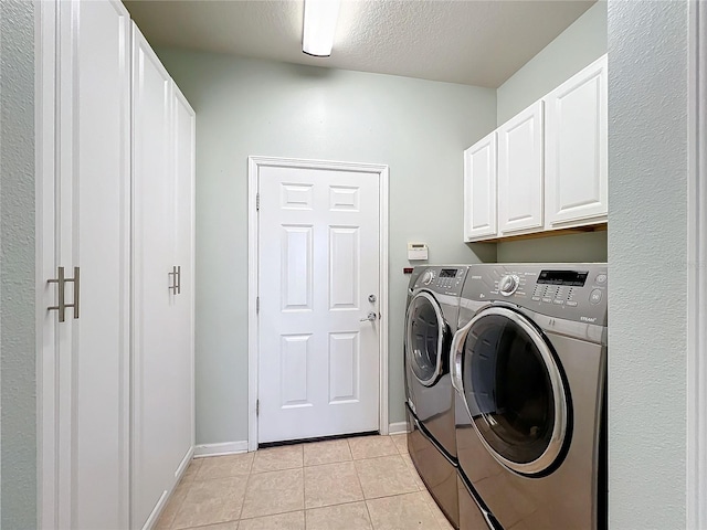 laundry area featuring light tile patterned floors, cabinet space, a textured ceiling, washer and dryer, and baseboards