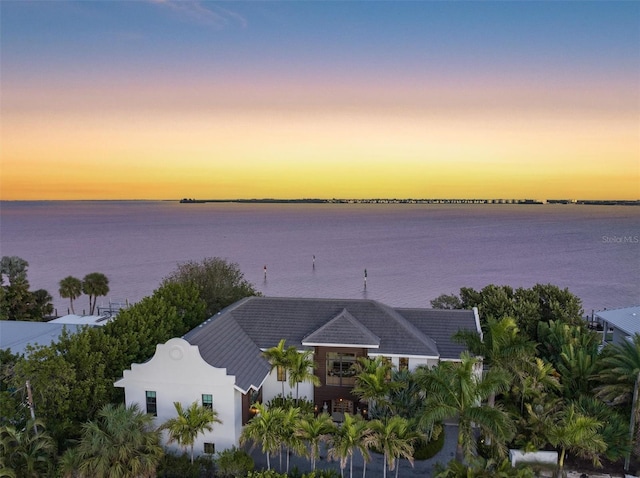 aerial view at dusk featuring a water view