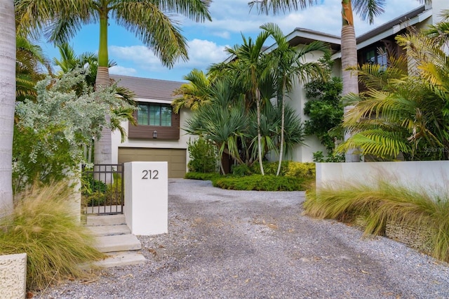 obstructed view of property with an attached garage, driveway, and a gate