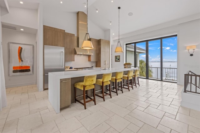 kitchen with light countertops, stainless steel built in fridge, high vaulted ceiling, wall chimney exhaust hood, and modern cabinets