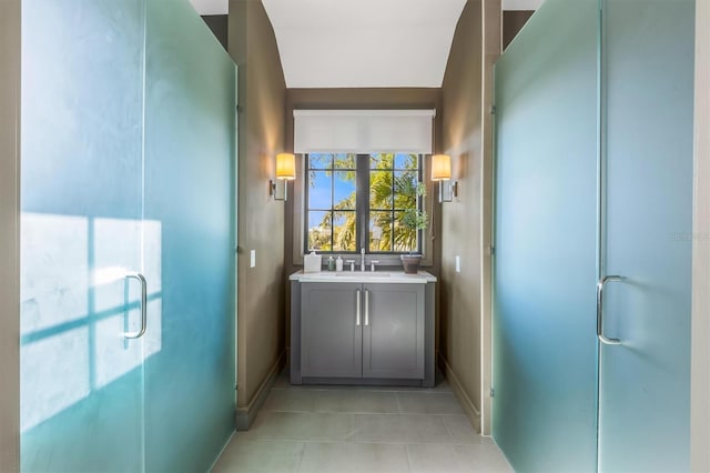 bathroom with tile patterned flooring, a shower stall, baseboards, and a sink