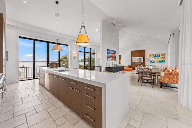 kitchen featuring a center island with sink, light countertops, stone tile flooring, modern cabinets, and a sink