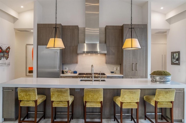 kitchen with tasteful backsplash, modern cabinets, light countertops, and wall chimney range hood