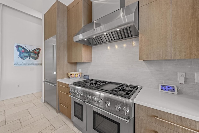 kitchen with backsplash, light countertops, wall chimney exhaust hood, modern cabinets, and high end appliances