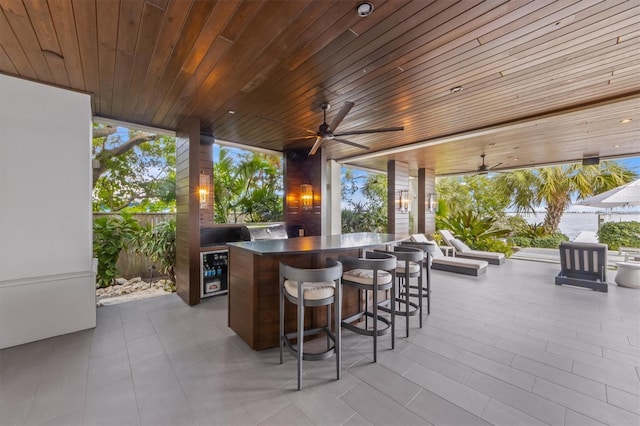 view of patio with outdoor wet bar, a ceiling fan, and fence