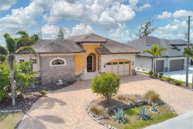 view of front facade featuring an attached garage, stone siding, a tiled roof, decorative driveway, and stucco siding