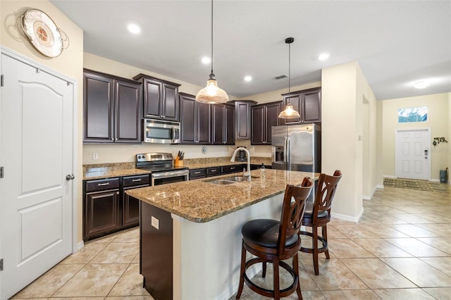 kitchen featuring light tile patterned floors, stainless steel appliances, a sink, visible vents, and light stone countertops