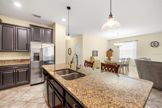 kitchen featuring dishwashing machine, a sink, visible vents, light stone countertops, and stainless steel fridge