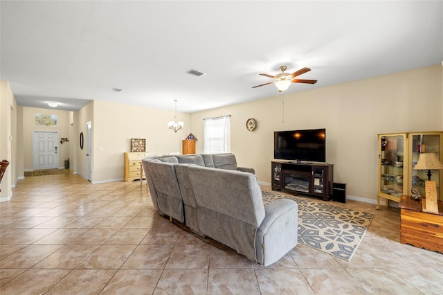 living room with ceiling fan with notable chandelier, visible vents, baseboards, and light tile patterned floors