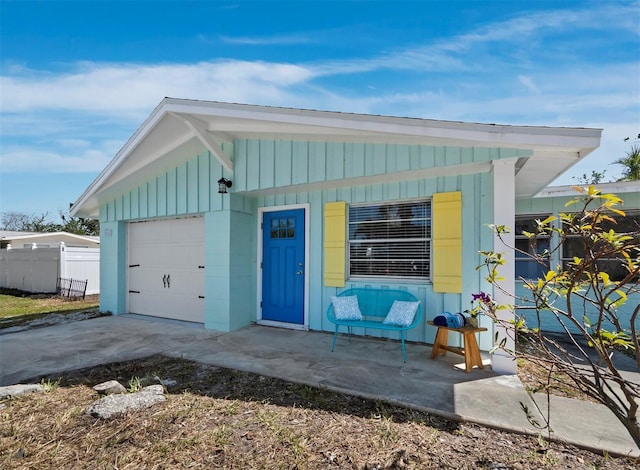 view of front of house featuring board and batten siding, concrete driveway, an attached garage, and fence